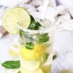 A Virgin Mojito cocktail with lime slices, mint leaves, and a straw in a sugar-rimmed glass.