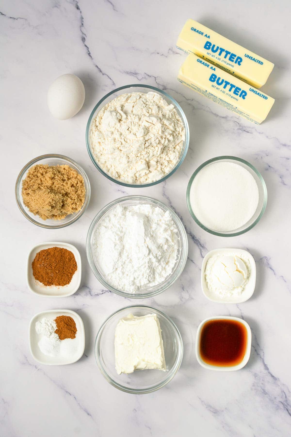 Baking ingredients on a marble surface: flour, butter, sugar, egg, spices, cream cheese, and vanilla&mdash;everything you need to whip up delicious cinnamon swirl cookies or your favorite Crumbl copycat cookies.
