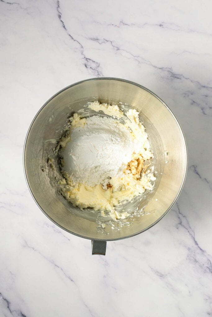 A mixing bowl with flour, butter, and sugar being combined on a marble countertop for homemade Crumbl copycat cookies.