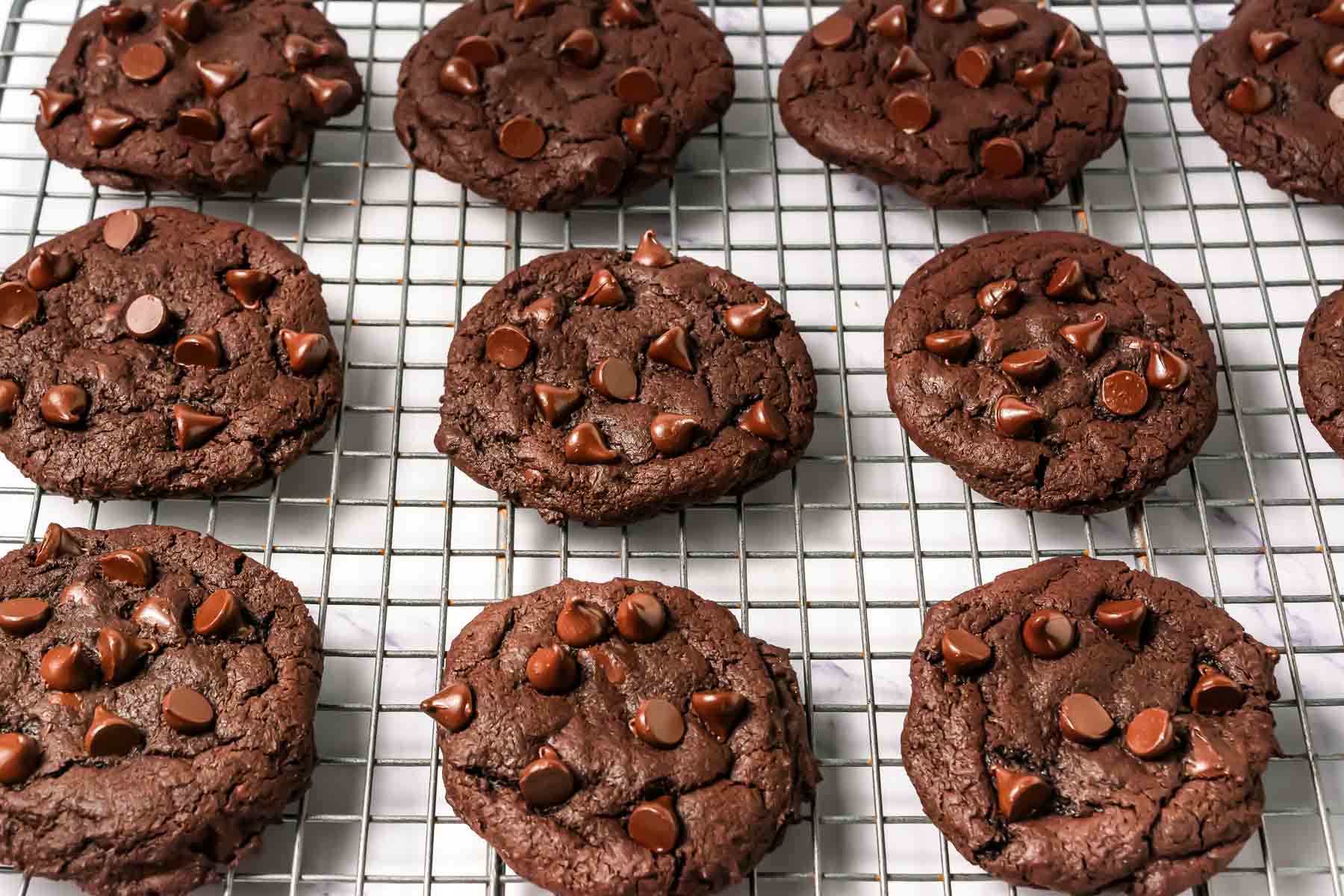 Chocolate cookies with chocolate chips cooling on a wire rack&mdash;these dark dream cookies are a delicious Crumbl copycat cookie you&rsquo;ll want to make again and again.