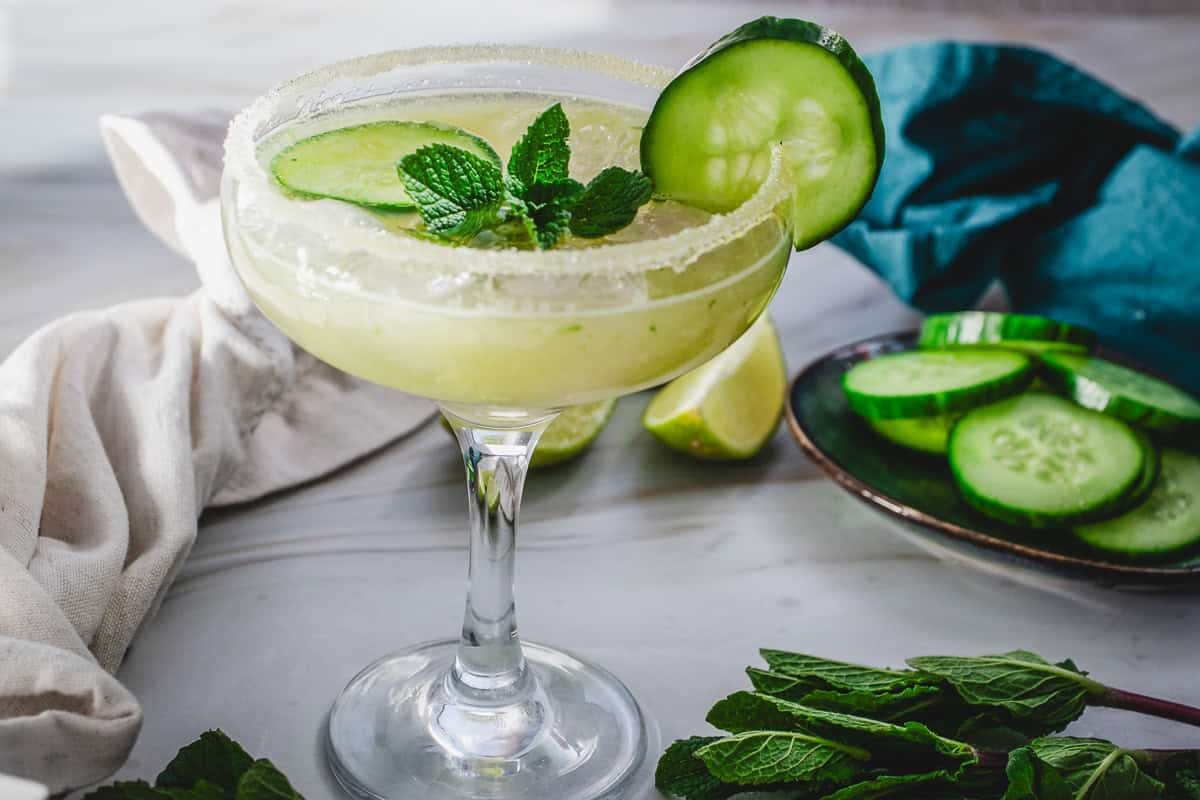 A refreshing Cucumber Margarita Mocktail garnished with cucumber slices and mint in a sugar-rimmed glass.