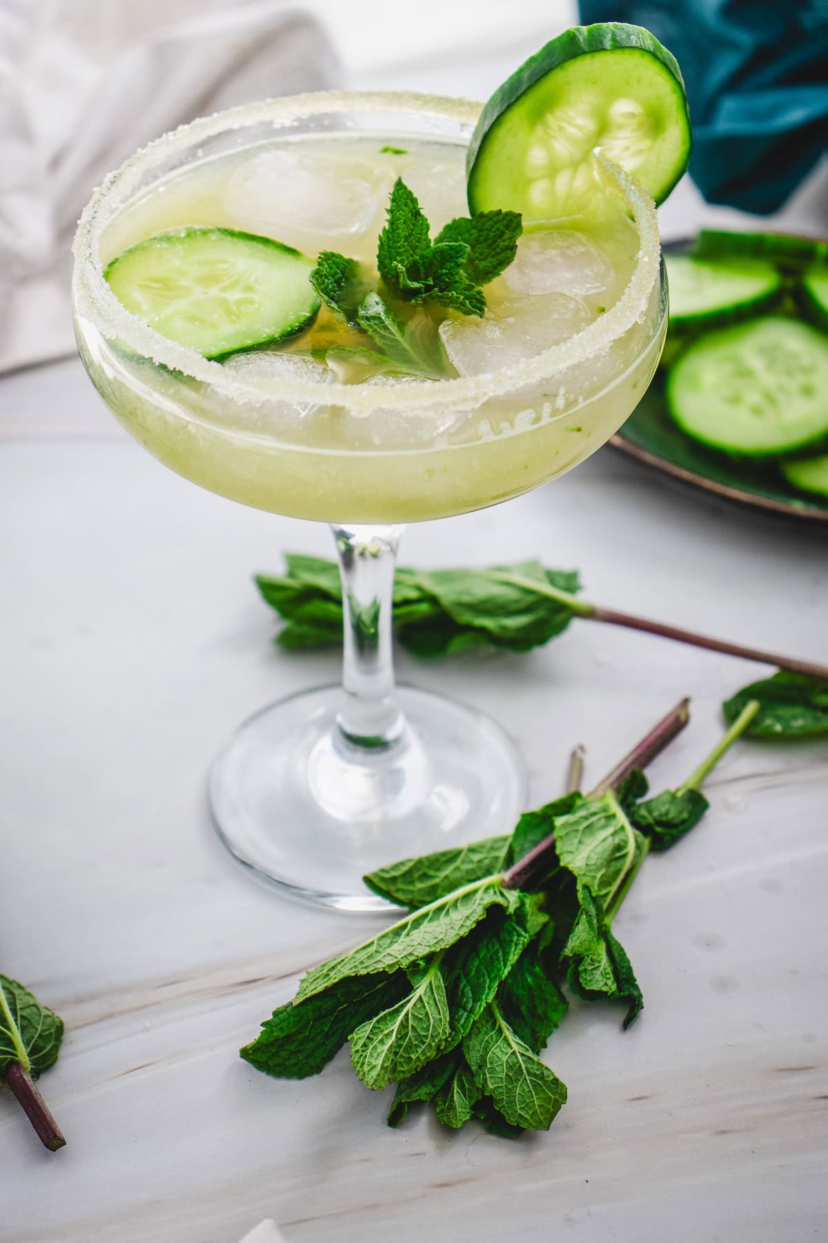 A Cucumber Margarita Mocktail garnished with cucumber slices and mint, served in a sugar-rimmed glass with ice.