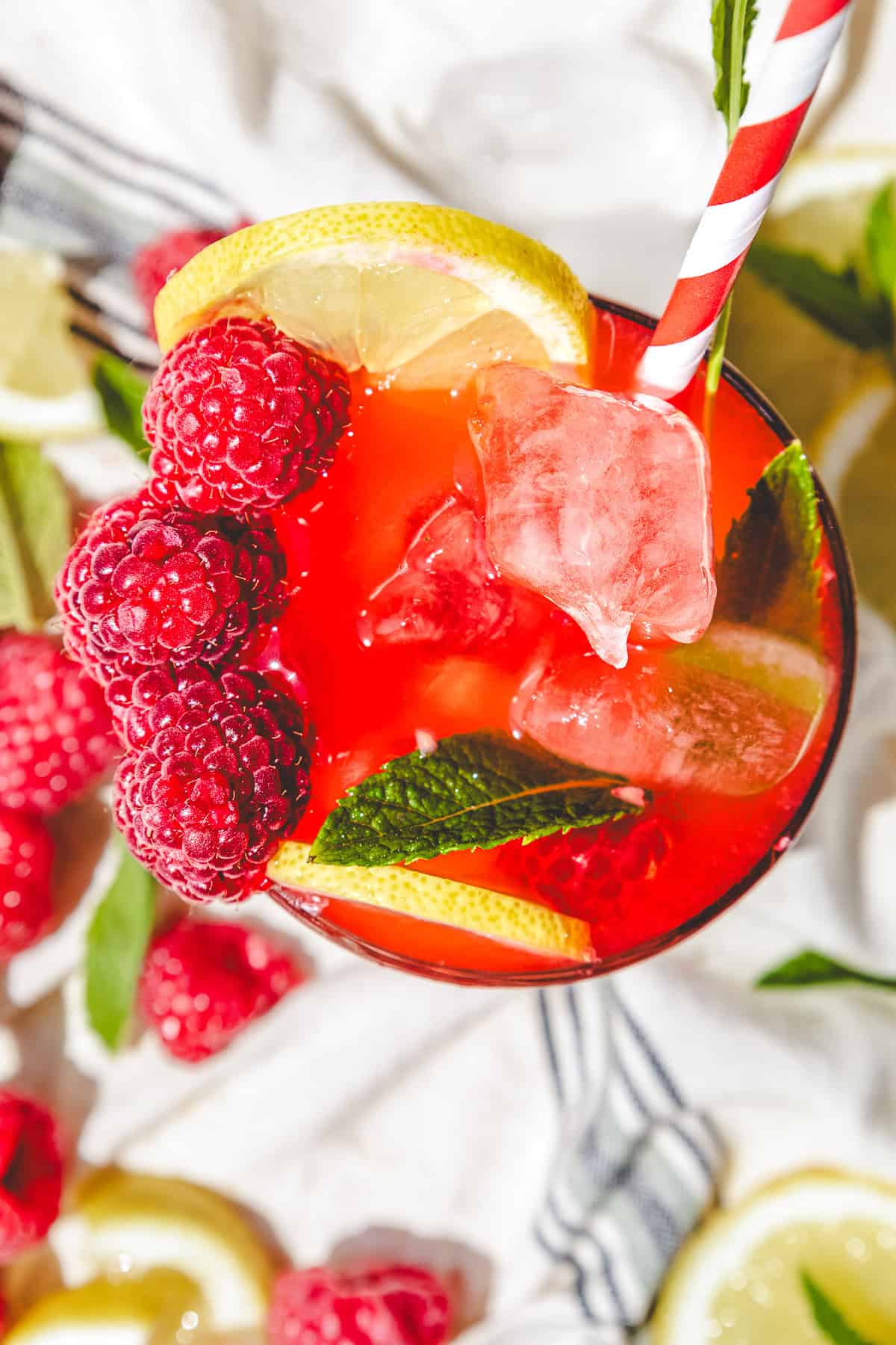 A glass of red drink with raspberries and lemons, perfect for trying a refreshing raspberry mojito mocktail recipe.