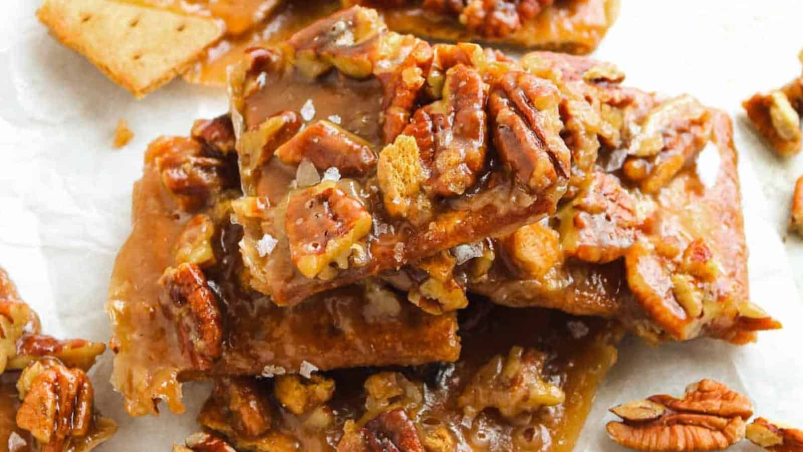Close-up of pecan pie bark with caramelized pecans on top of graham crackers, arranged on parchment paper.