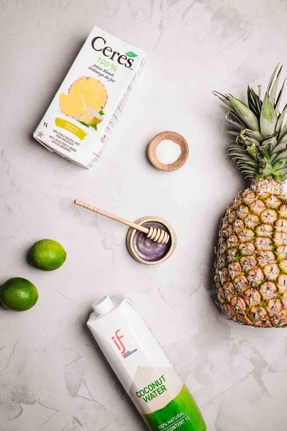 A pineapple and a box of juice, perfect ingredients for a refreshing Tropical Electrolyte Mocktail.