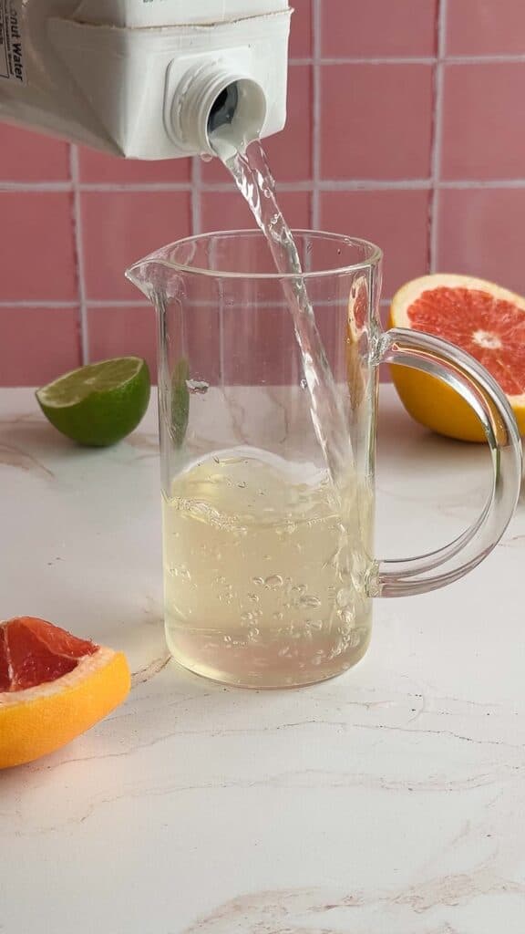 A glass pitcher with liquid in it and fresh grapefruit on the counter&mdash;perfect for your next electrolyte-rich mocktail recipe.