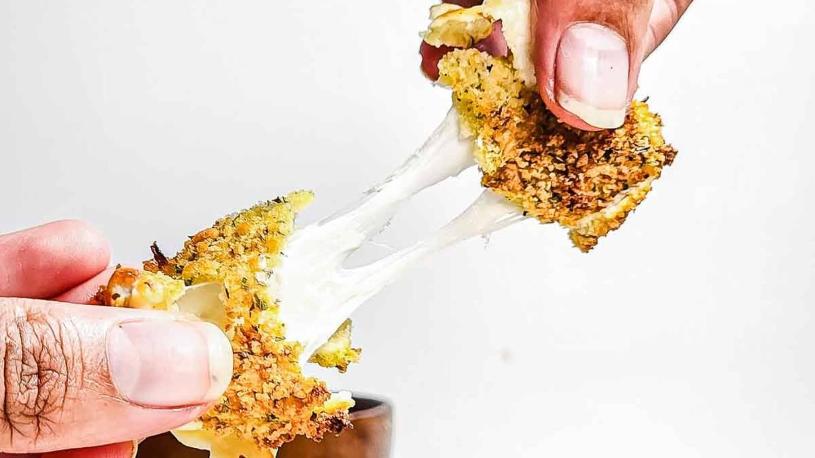 Close-up of crispy, breaded cheese bites with melted cheese on a wooden board.