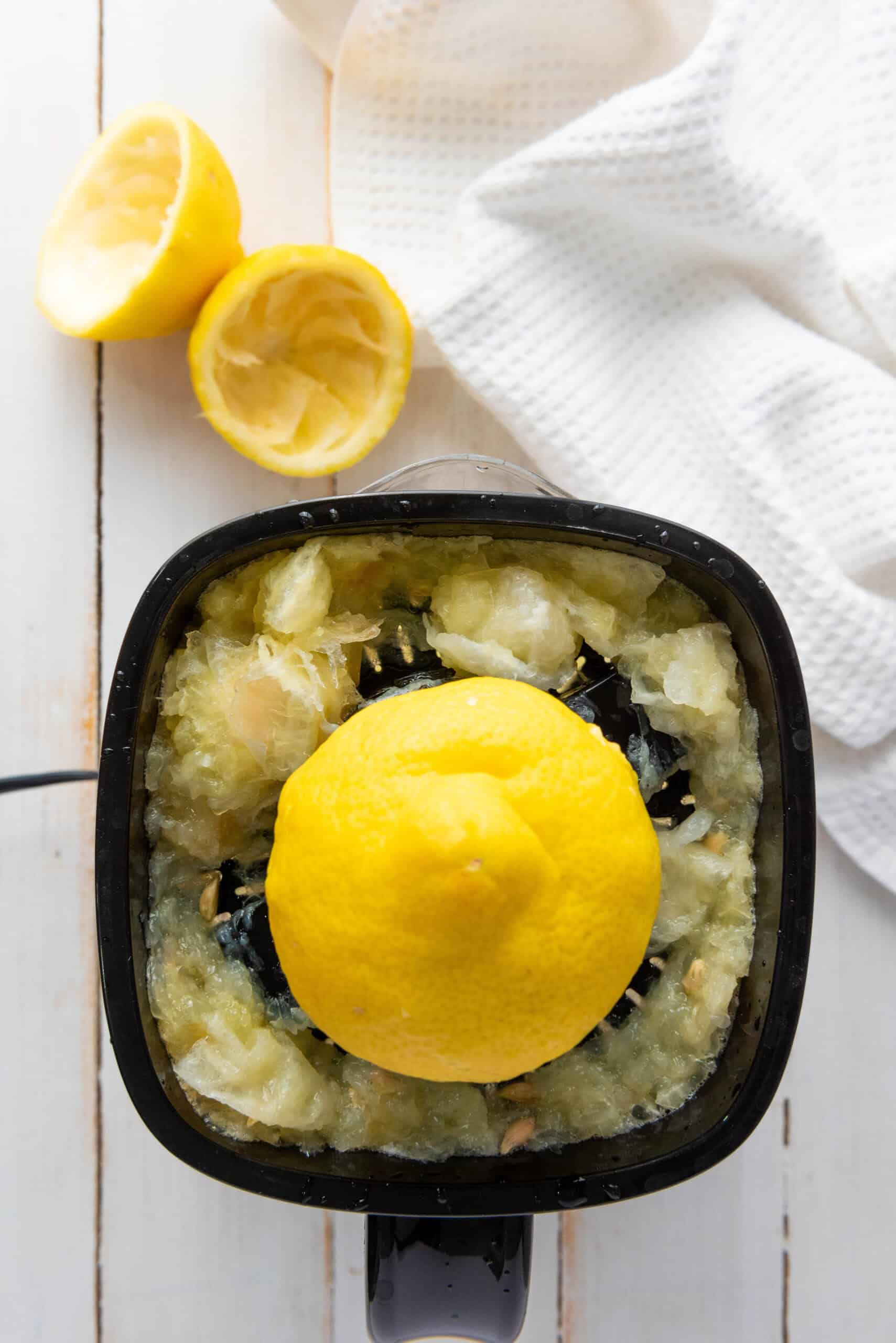 Overhead view of a lemon juicer with a half lemon, lemon pulp, and squeezed halves beside it&mdash;perfect for your next homemade lemonade recipe.