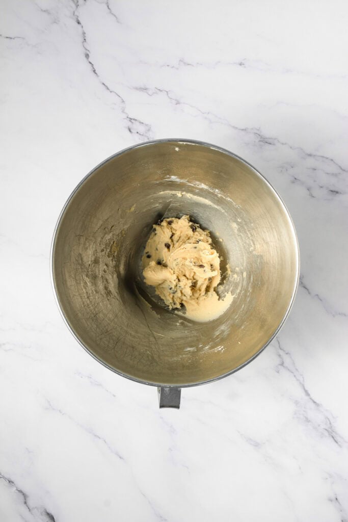A metal mixing bowl with Crumbl copycat cookie dough cookies inside, sitting on a white marble surface.