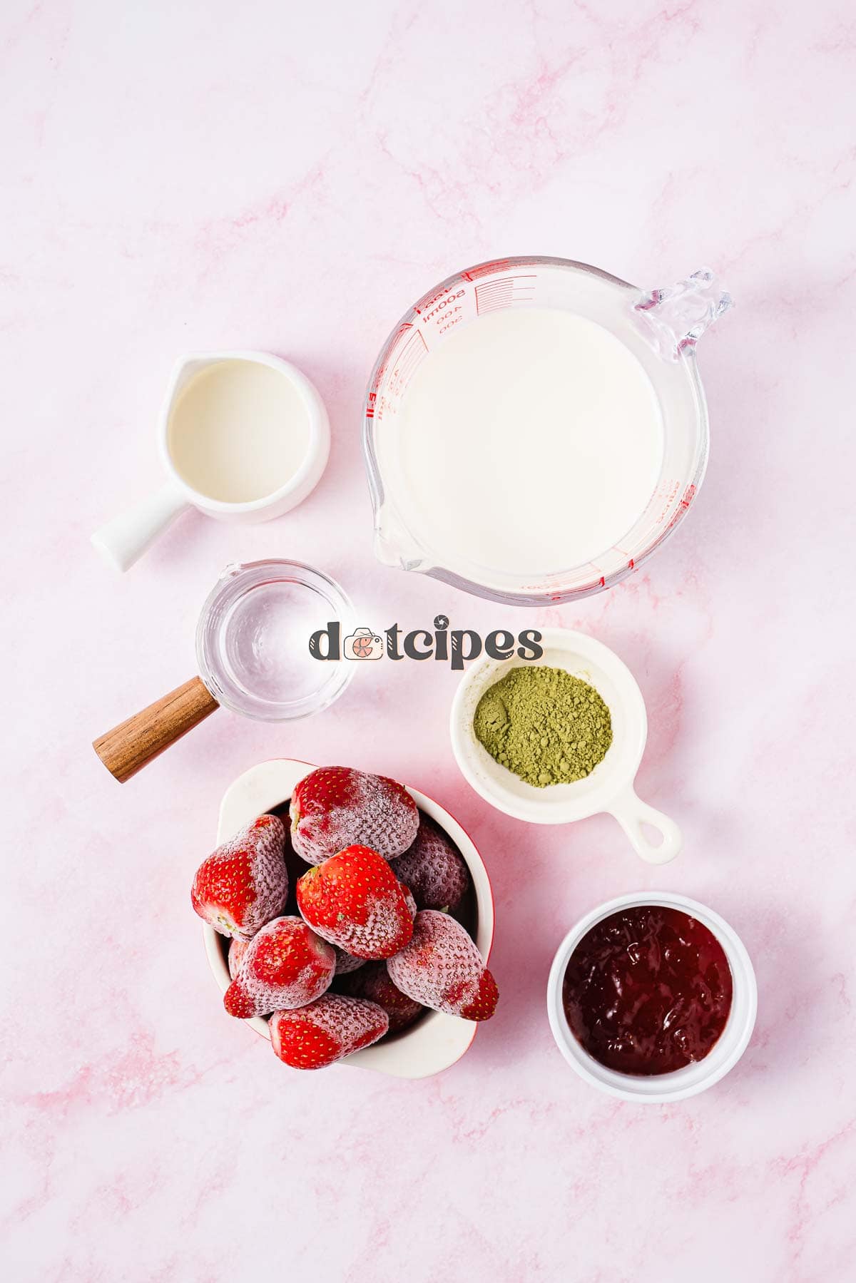 Bowls with frozen strawberries, matcha powder, jam, milk, cream, and a glass of water on a pink background&mdash;perfect for crafting a refreshing Strawberry Matcha Recipe.