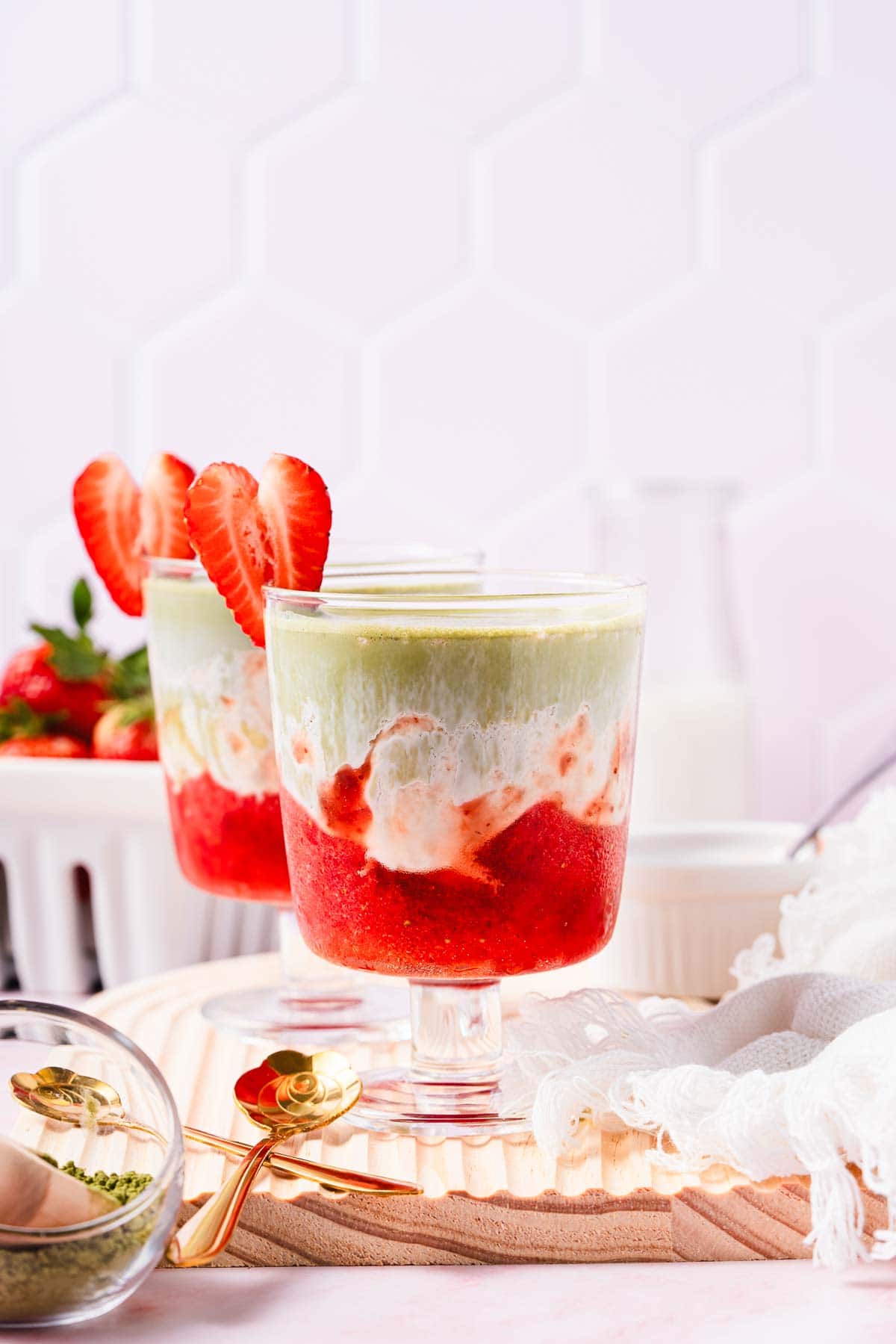 Layered strawberry, cream, and matcha drinks in glass cups, garnished with fresh strawberry slices&mdash;a delicious Strawberry Matcha recipe perfect for any occasion.