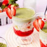 Layered Strawberry Matcha parfait in a glass, garnished with a sliced strawberry on the rim—a deliciously refreshing Strawberry Matcha Recipe you'll love to try.