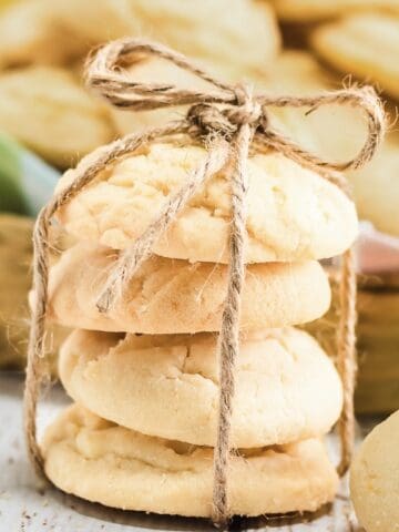 Stack of four Amish lemon cookies tied with twine, with more cookies blurred in the background.