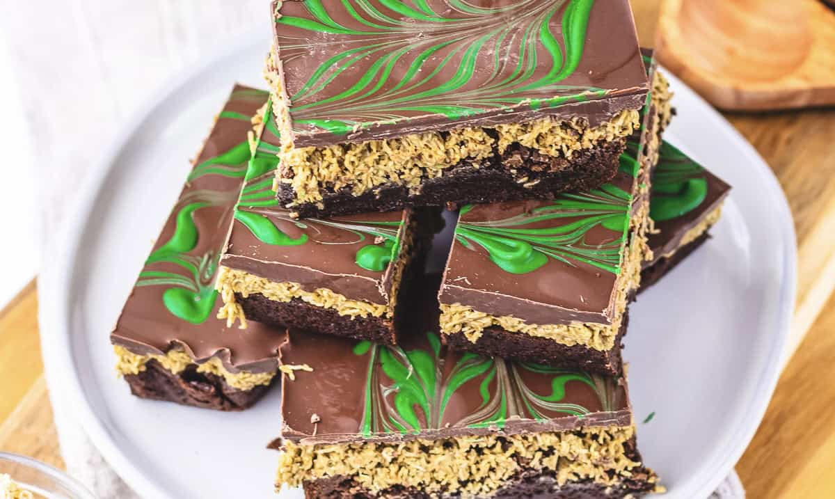 A plate of Dubai Chocolate Brownie bars with a green swirl pattern on top and a layer of oat filling in the middle, perfect for anyone seeking an irresistible Dubai Dessert treat.
