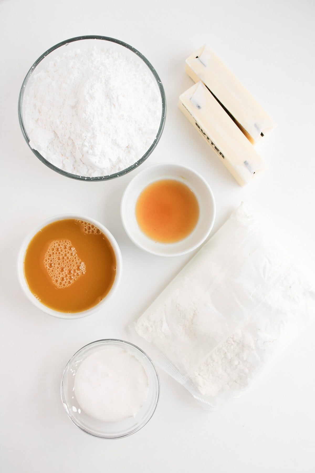 Bowl of powdered sugar, butter sticks, honey, vanilla, flour, and milk on a white background&mdash;perfect ingredients for creating delicious Dole Whip Cupcakes.