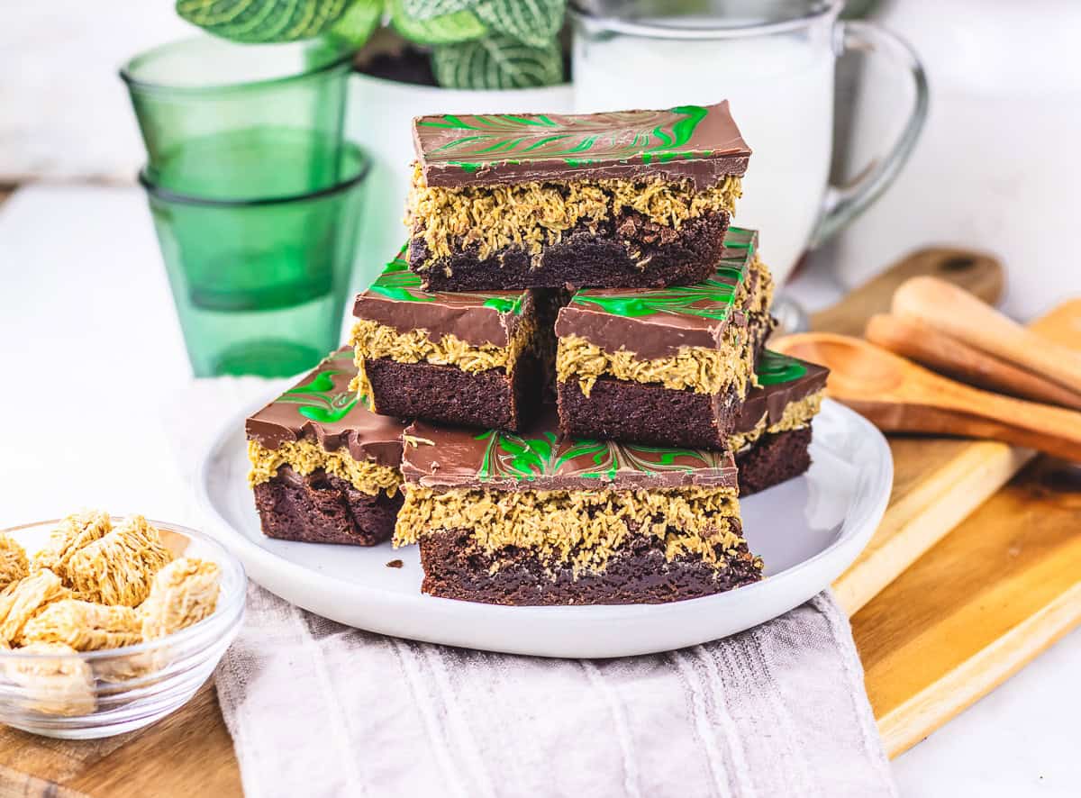 A plate of chocolate-topped layered dessert bars with a green swirl pattern, inspired by the Dubai Chocolate Brownie Recipe, stacked neatly on a plate.