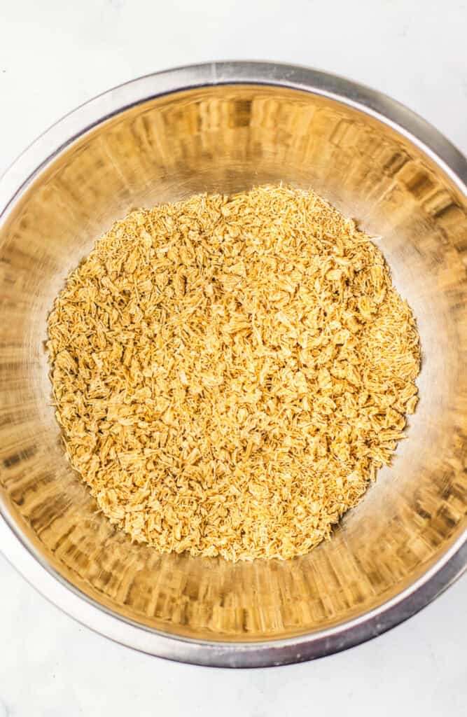 Stainless steel bowl filled with dried, shredded onions on a white surface&mdash;essential for adding savory depth to dishes like the Dubai Chocolate Brownie Recipe.