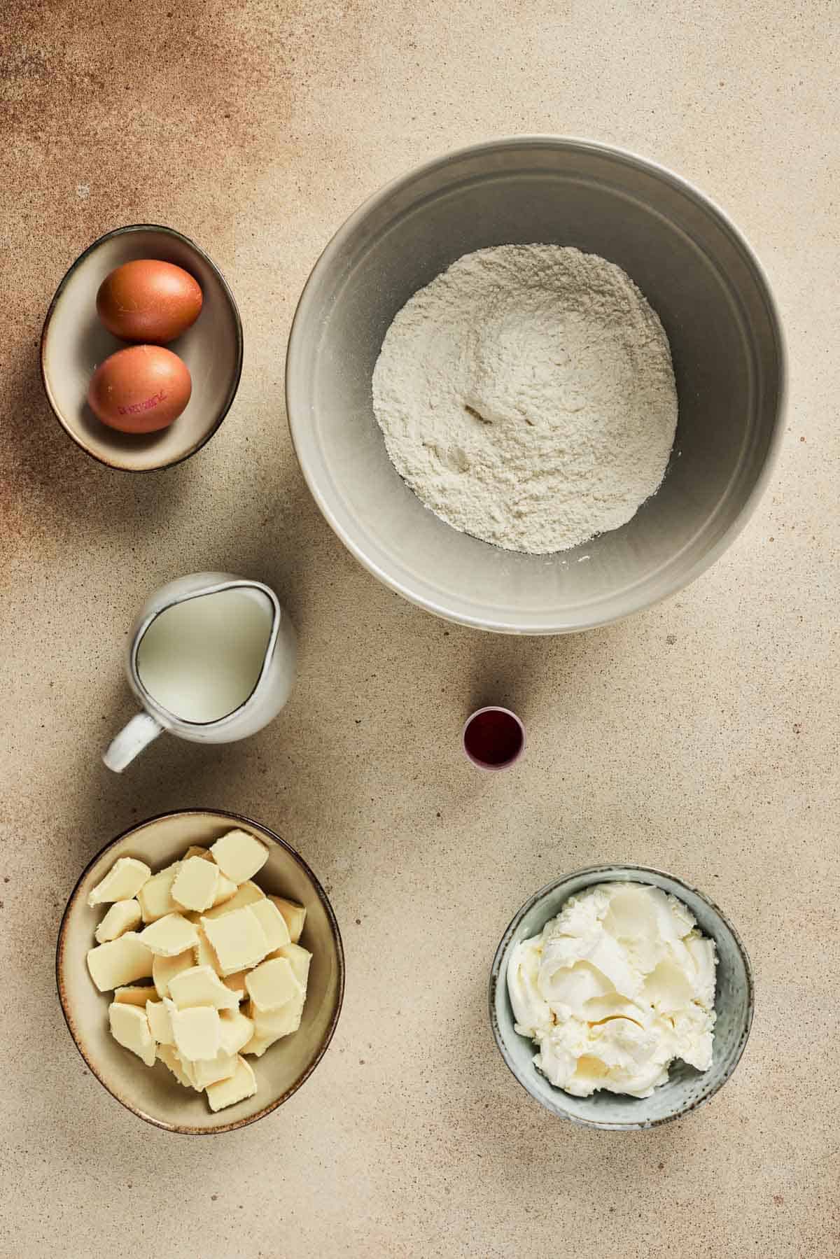 Baking ingredients including flour, eggs, milk, butter, cream, and vanilla arranged on a countertop&mdash;perfect for preparing Strawberry Cake Balls or any delightful strawberry dessert.