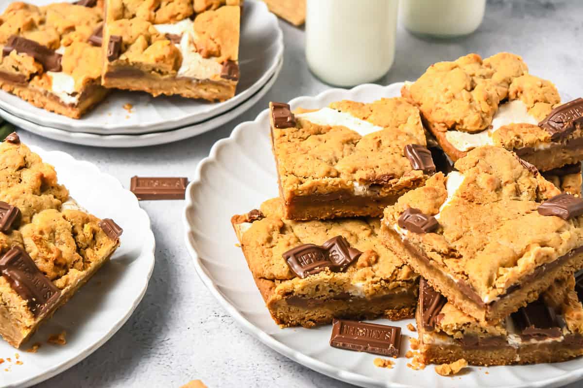 Plates of S&rsquo;mores Bars with chocolate chunks and marshmallow, next to glasses of milk&mdash;an irresistible s&rsquo;mores dessert perfect for sharing.