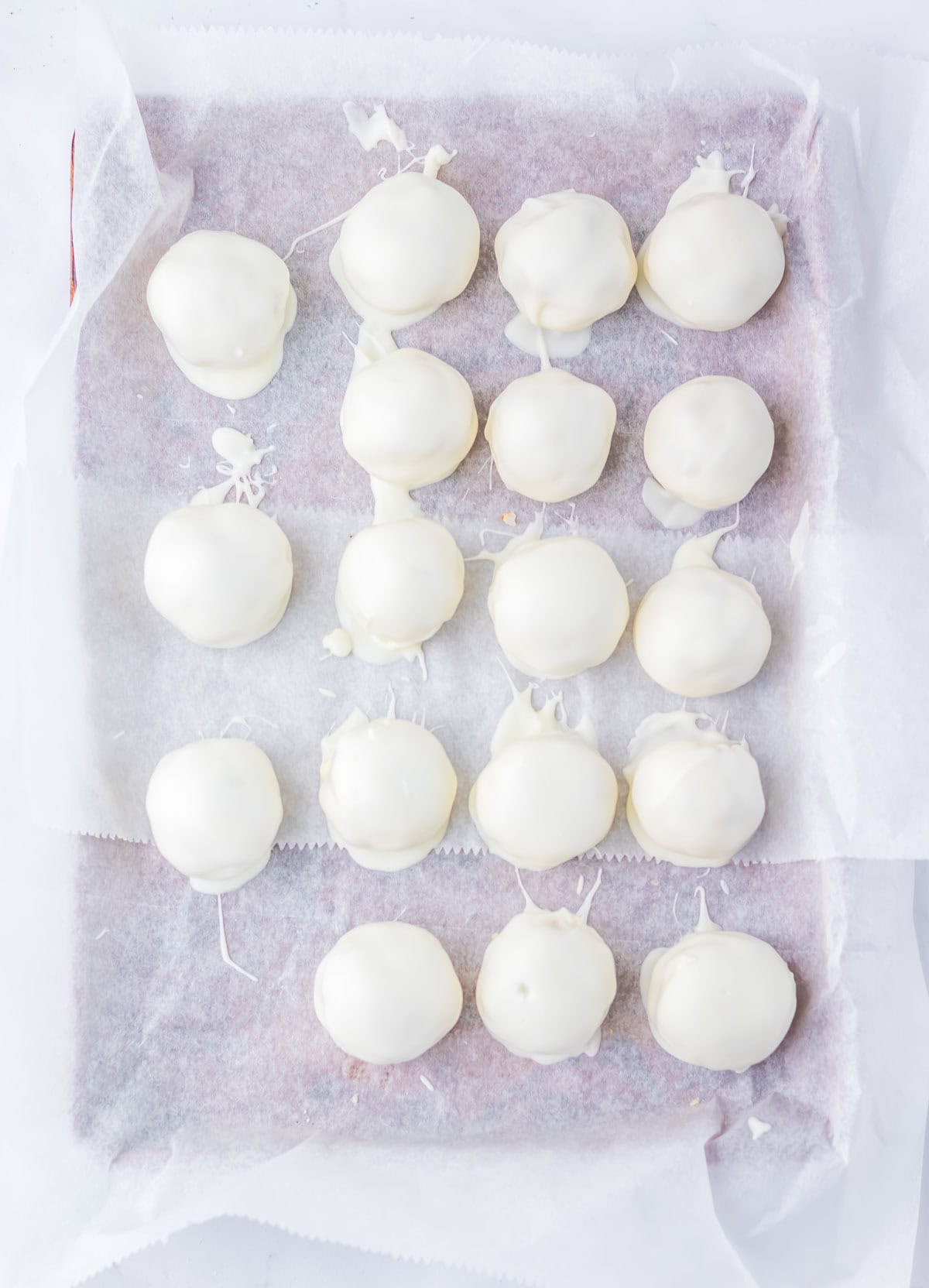 A tray of Zebra Cake Balls&mdash;round, white chocolate-coated treats&mdash;arranged neatly in rows on parchment paper.