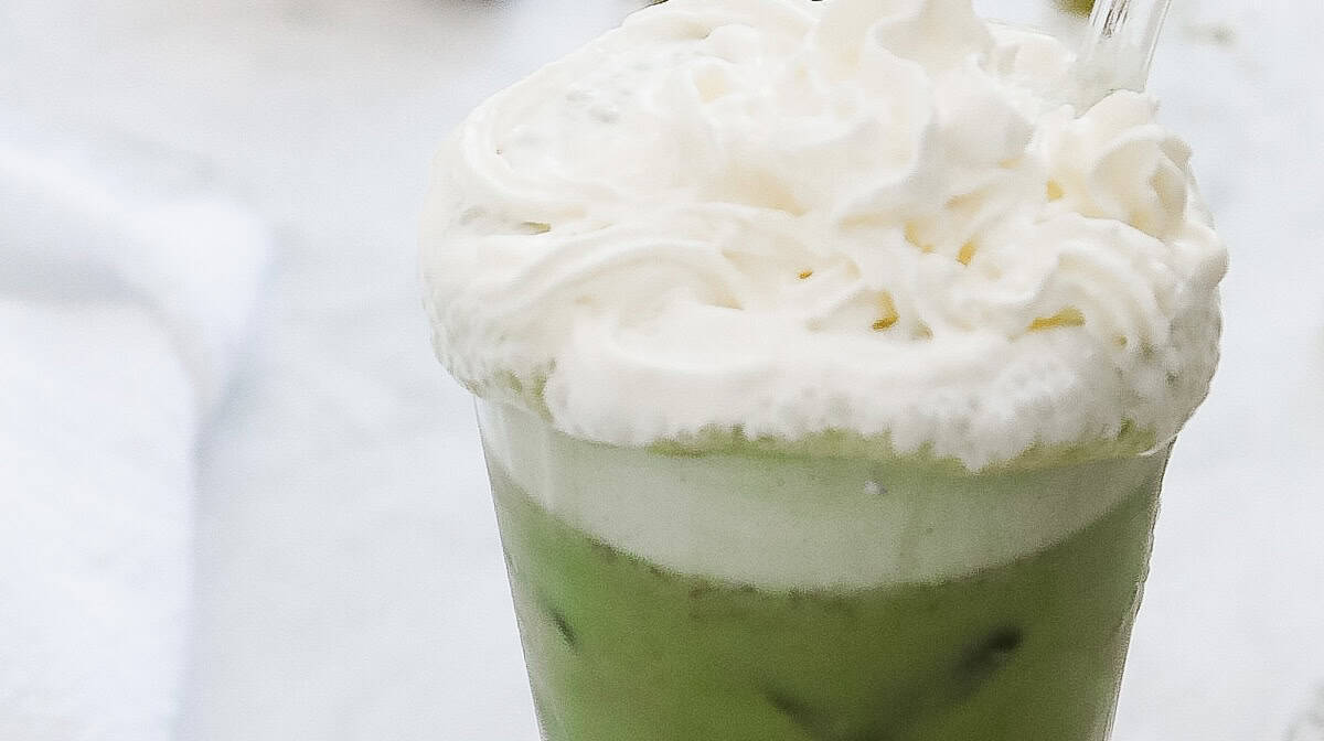 Iced matcha latte topped with whipped cream in a glass with a straw&mdash;a delicious copycat recipe inspired by Starbucks Green Tea Frappuccino.