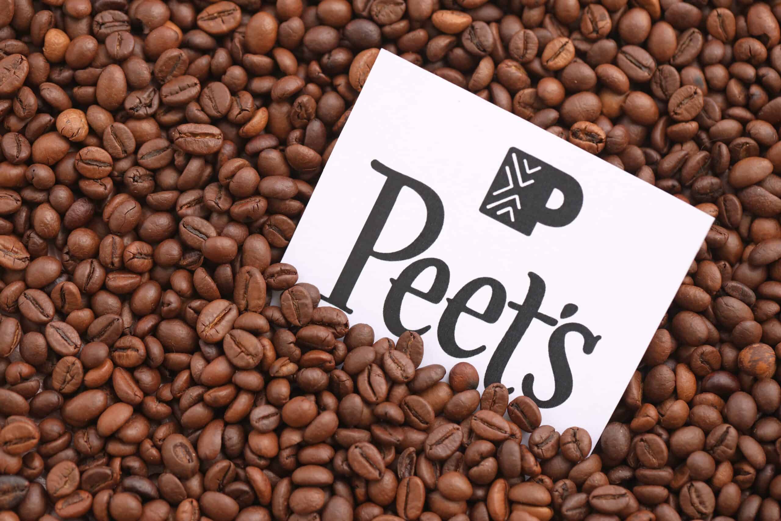 A Peet's Coffee card partially buried in a pile of roasted coffee beans, showcasing the rich aroma of the best ground coffee.