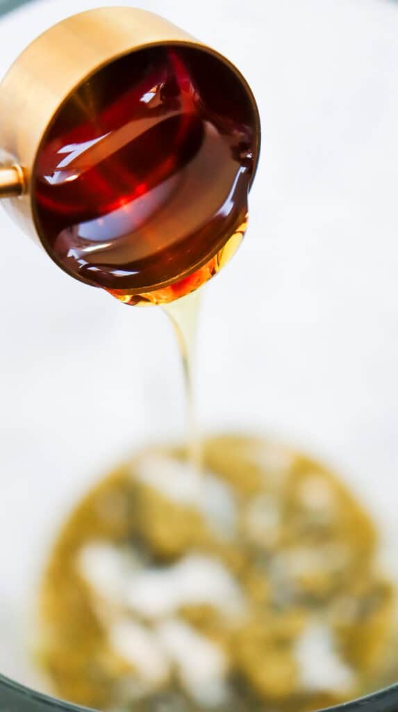 Honey being poured from a copper measuring cup into a bowl with a blurred background, perfect for a Starbucks Copycat Recipe like the Green Tea Frappuccino.