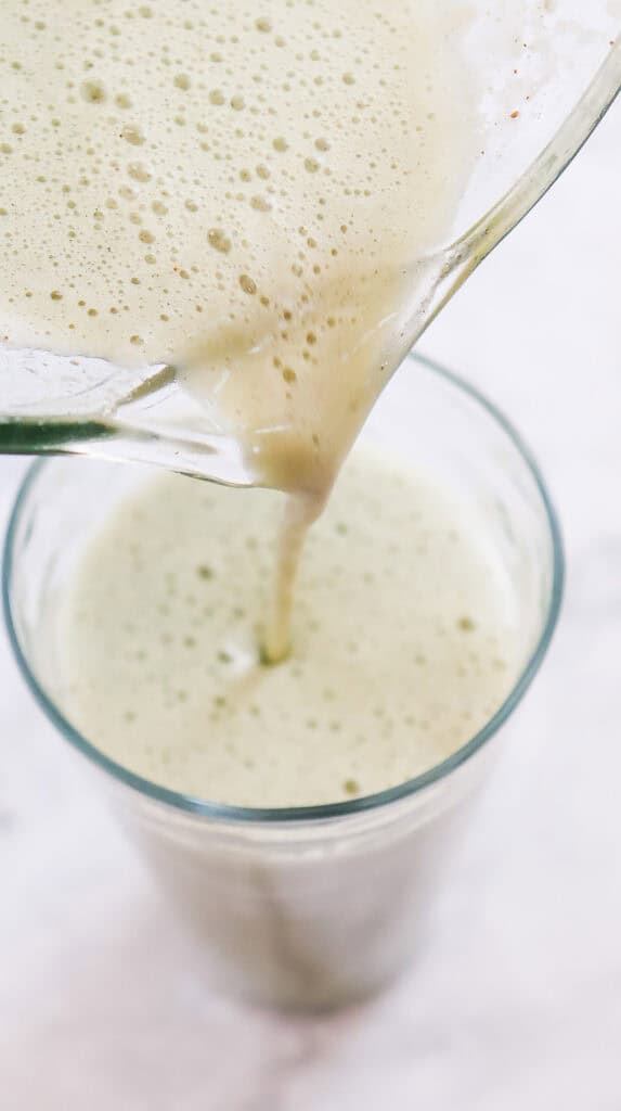 A creamy green smoothie, inspired by the Starbucks Green Tea Frappuccino, is being poured from a blender into a glass&mdash;a perfect copycat recipe for matcha lovers.