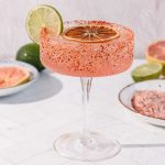 Spicy Grapefruit Margarita Mocktail in a glass with chili powder rim, garnished with lime and dried orange slices; a refreshing non-alcoholic treat.