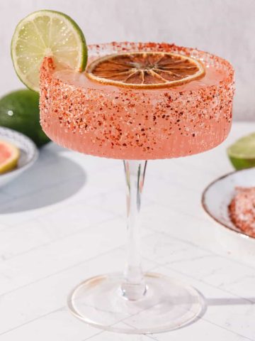 Spicy Grapefruit Margarita Mocktail in a glass with chili powder rim, garnished with lime and dried orange slices; a refreshing non-alcoholic treat.