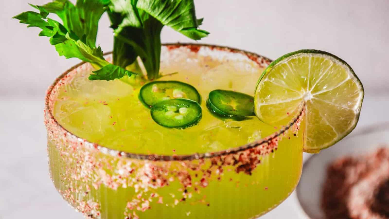 A spicy margarita garnished with lime, jalapeño slices, celery, and a chili-salt rim.