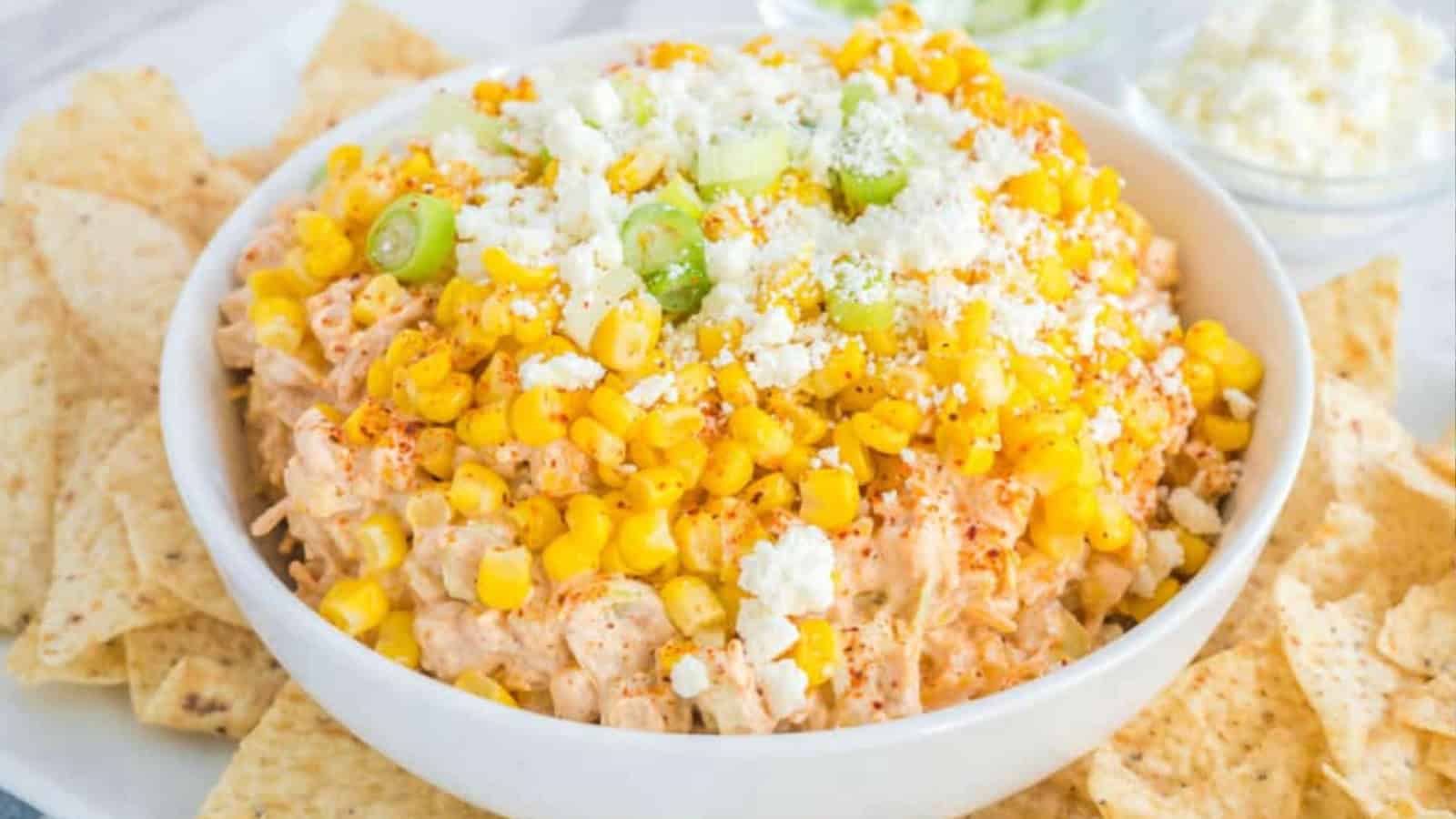 Mexican corn dip topped with cheese, herbs, and jalape&ntilde;os in a serving bowl.