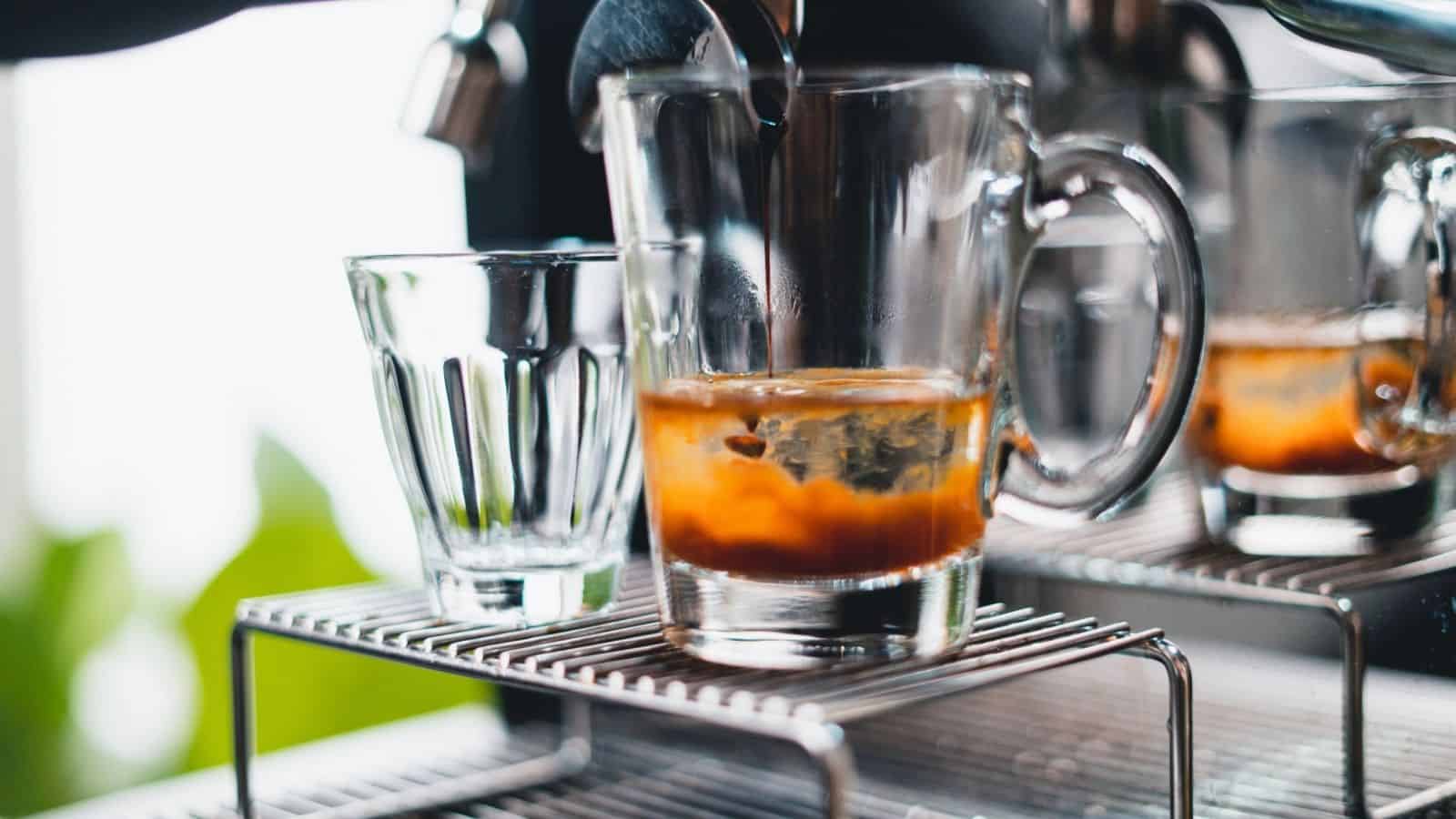Espresso pours into a clear glass mug from a coffee machine, with an empty glass beside it—perfect inspiration for your home café or new coffee bar ideas.