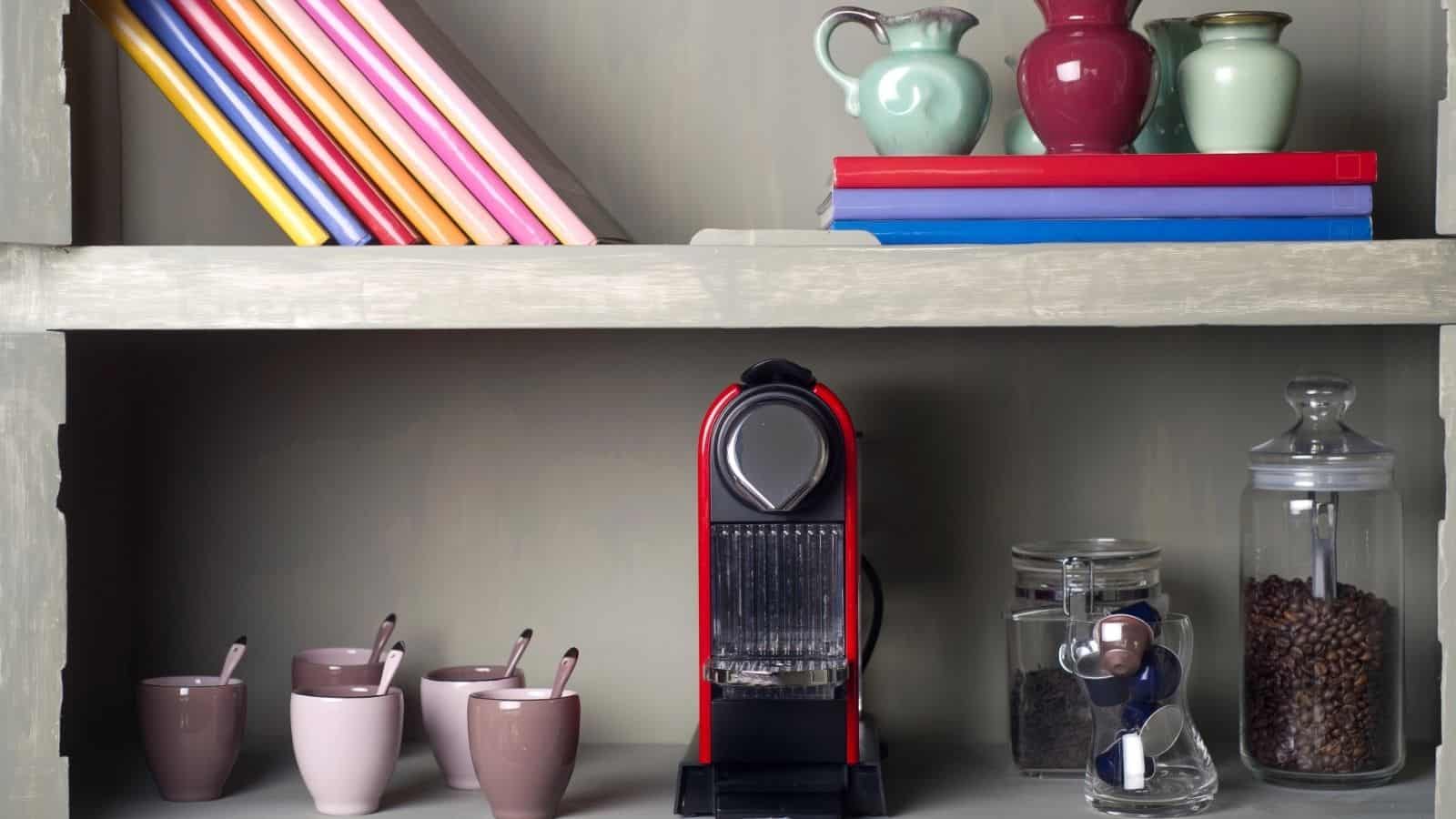 Shelf with books, mugs, a coffee machine, jars of coffee beans, and colorful vases—perfect inspiration for your home café or as part of unique coffee bar ideas.