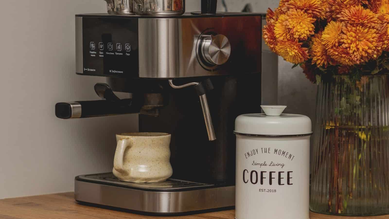 Espresso machine with mug, coffee canister, and a vase of orange flowers on a wooden countertop—perfect inspiration for your home café or stylish coffee bar ideas.