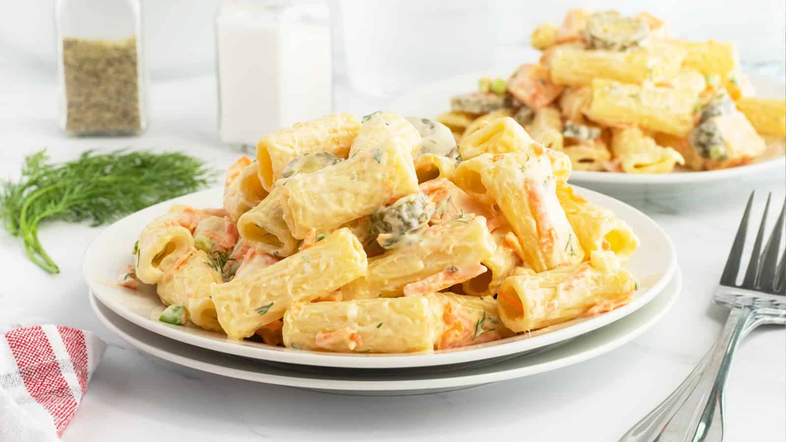 A plate of creamy pasta with herbs and vegetables, served on a white plate with forks nearby.