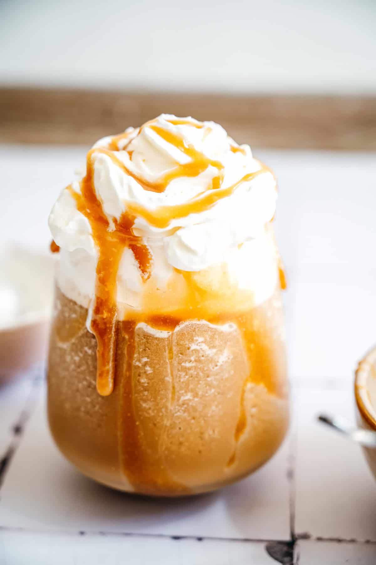 Iced coffee with whipped cream and caramel sauce drizzled on top in a clear glass, reminiscent of a refreshing Caramel Frappuccino.
