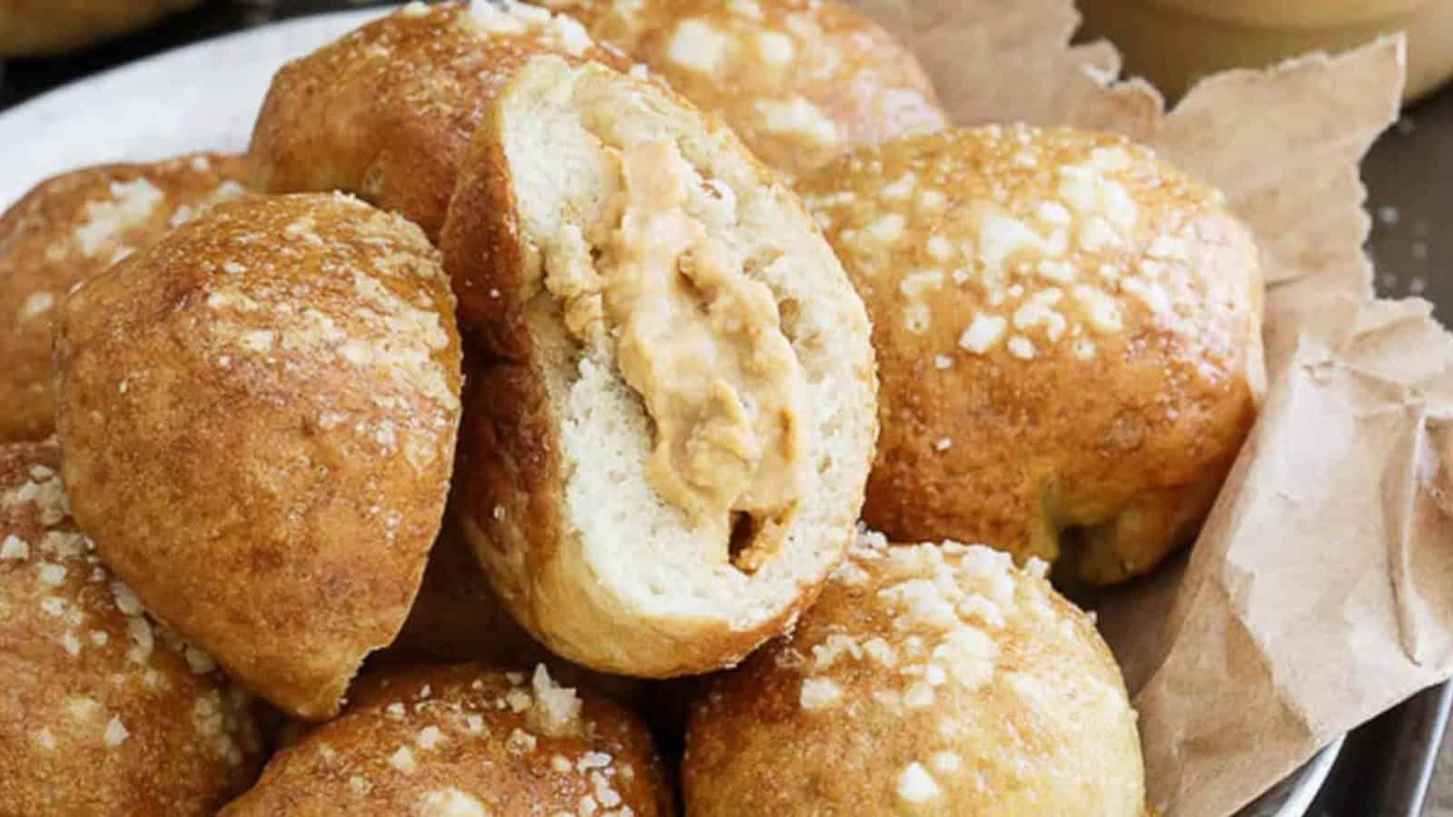 A pile of pretzel bites, one split open showing a creamy peanut butter filling inside.