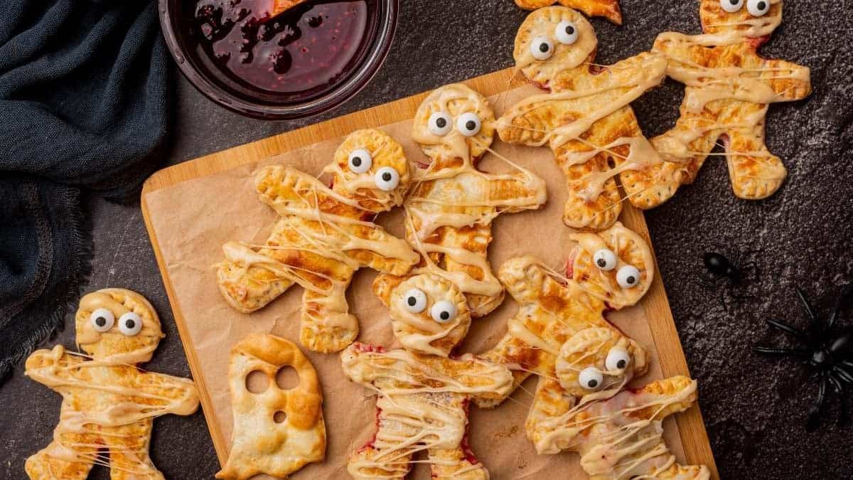 Halloween mummy hand pies decorated with strips of pastry and candy eyes.