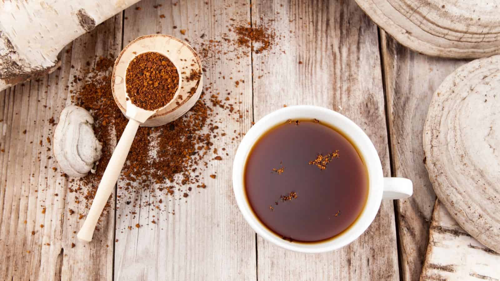 A cup of coffee sits on a wooden table with coffee grounds and a wooden scoop beside it, inviting you to explore 7 coffee alternatives for your next warm and comforting beverage.