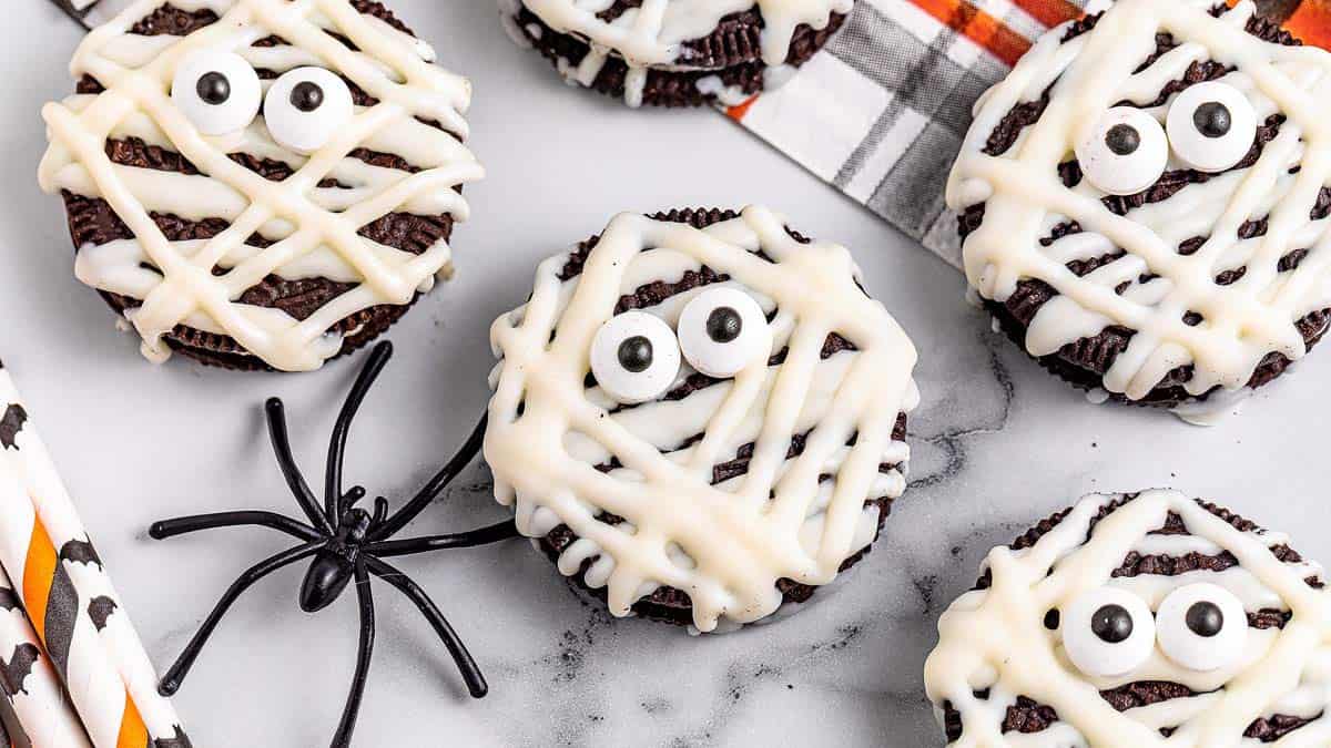 Oreo mummy cookies decorated with white icing and candy eyes.
