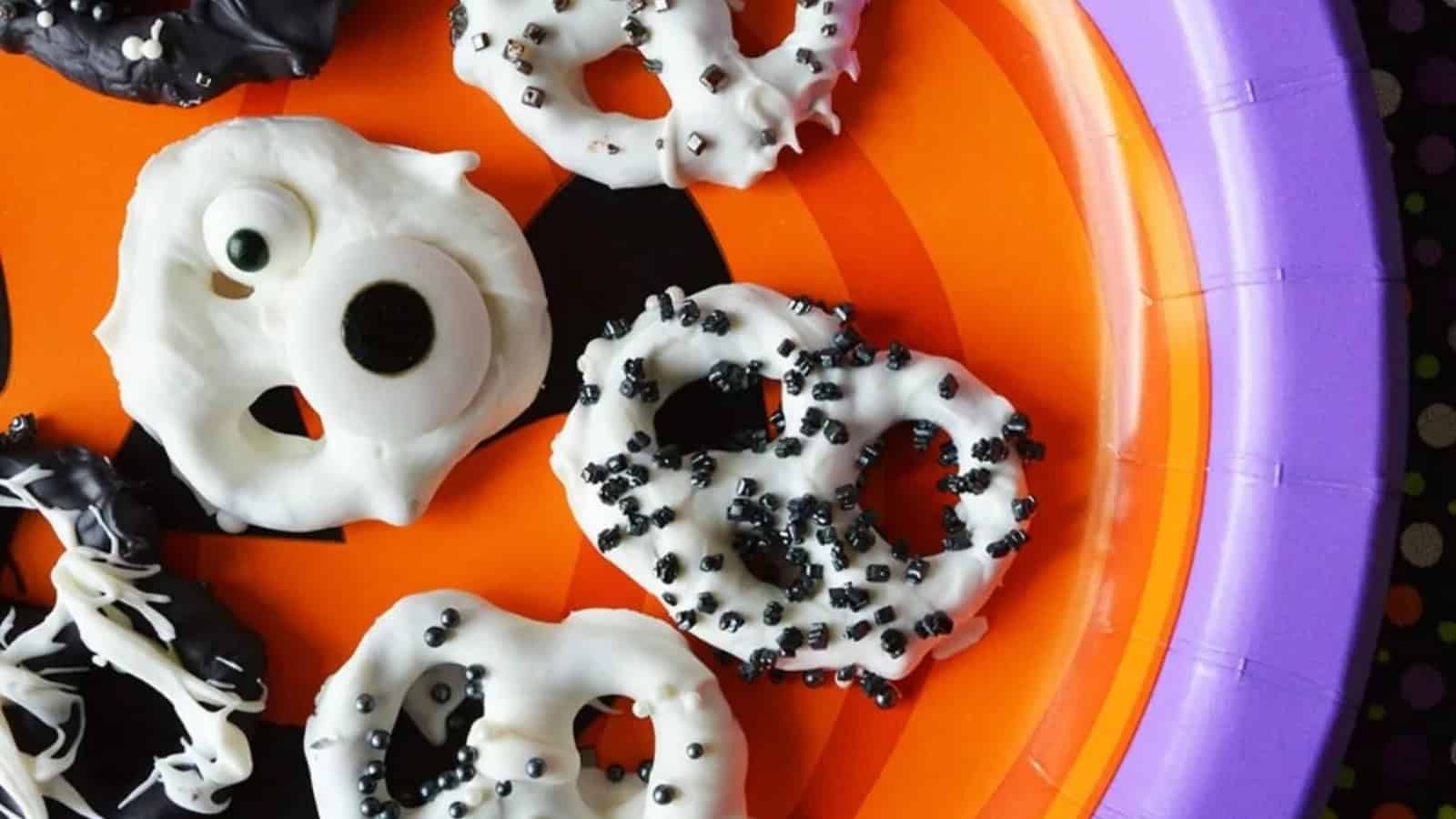 Halloween chocolate-covered pretzels decorated with colorful sprinkles and candy.