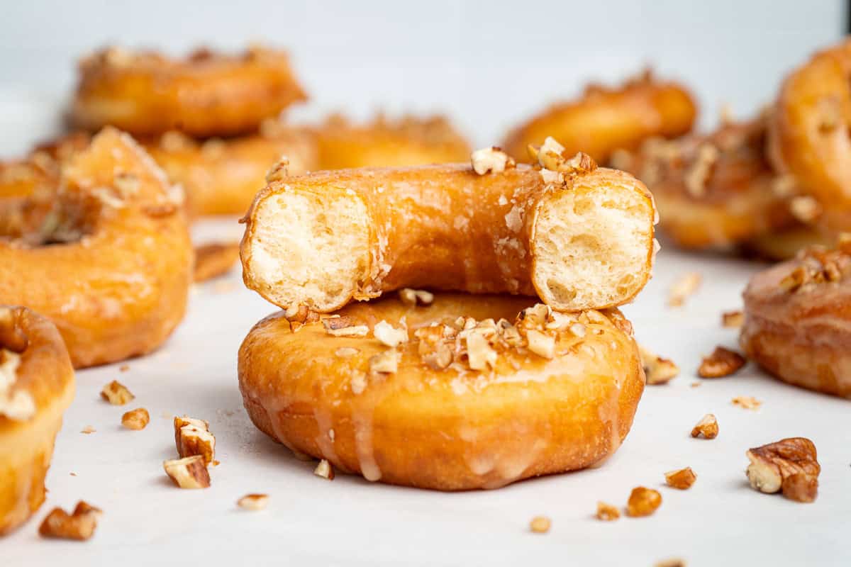 Glazed, maple-topped doughnuts with pecans, one split in half to show the interior.
