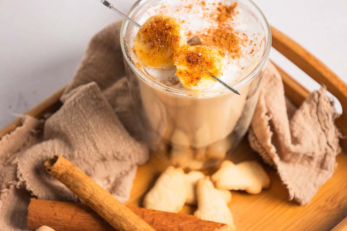 A creamy banana latte, like a Starbucks copycat, garnished with caramelized banana slices and cinnamon.
