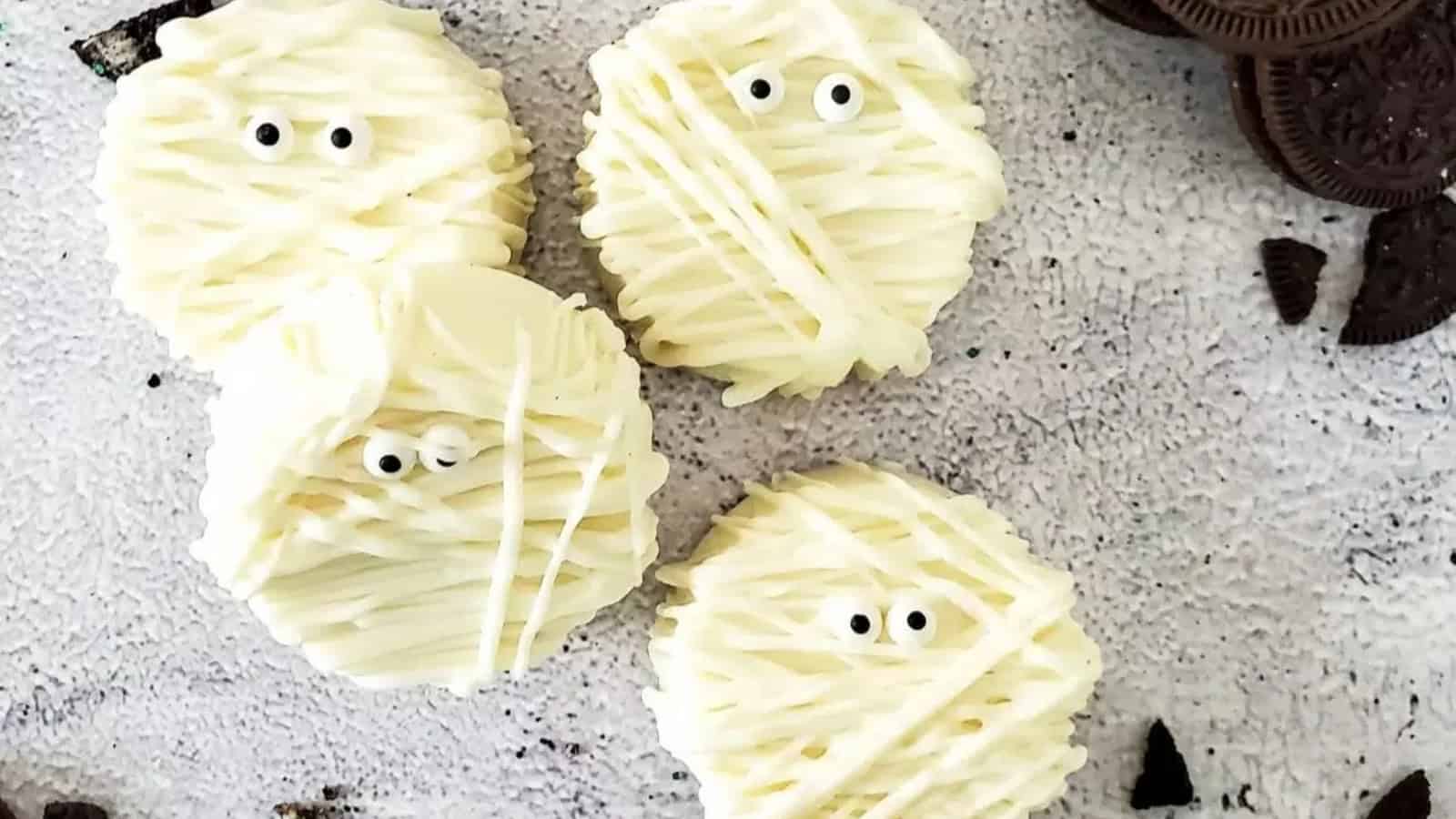 Mummy Halloween cookies decorated with white icing and candy eyes.