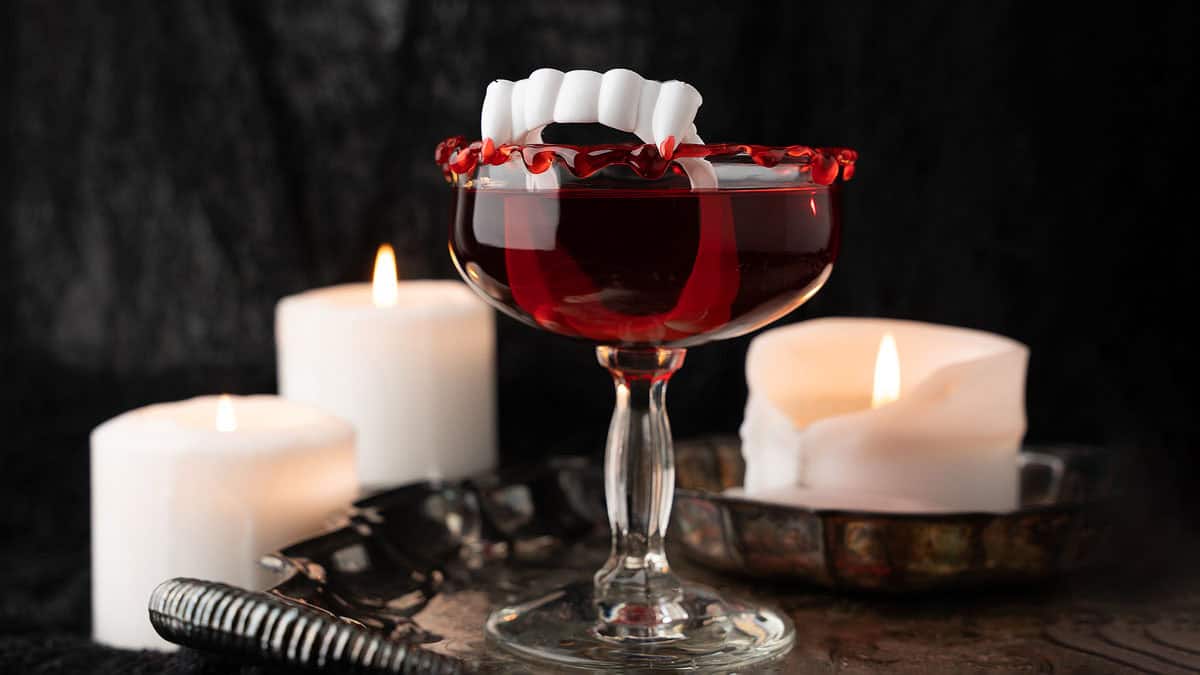 Cursed Immortal cocktail served in a glass with a dark red color and Halloween garnish.