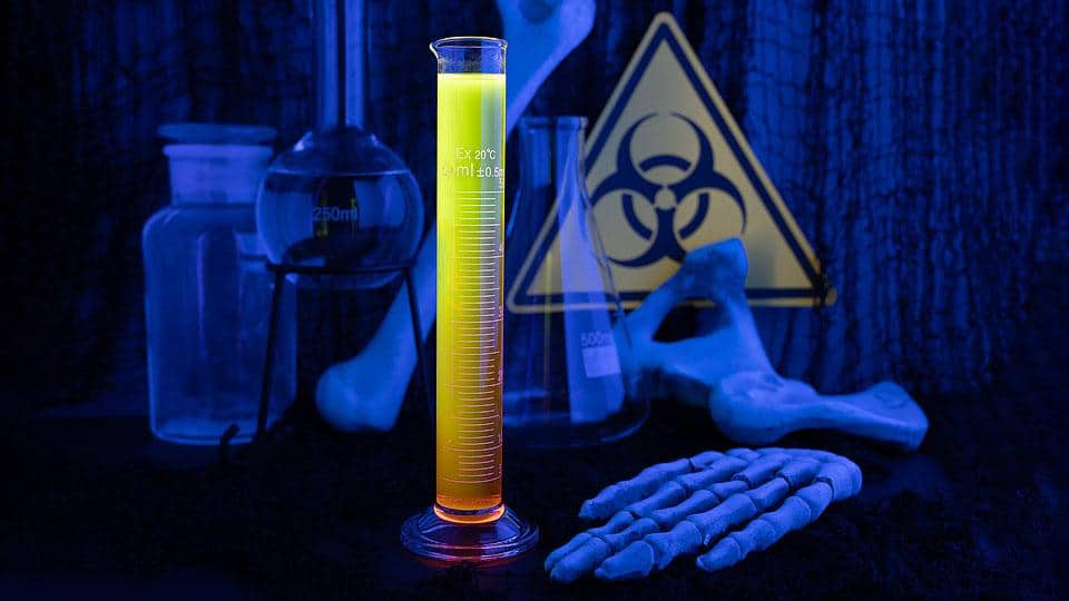 Glowing Halloween shooter cocktail with a bright fluorescent color under black light.