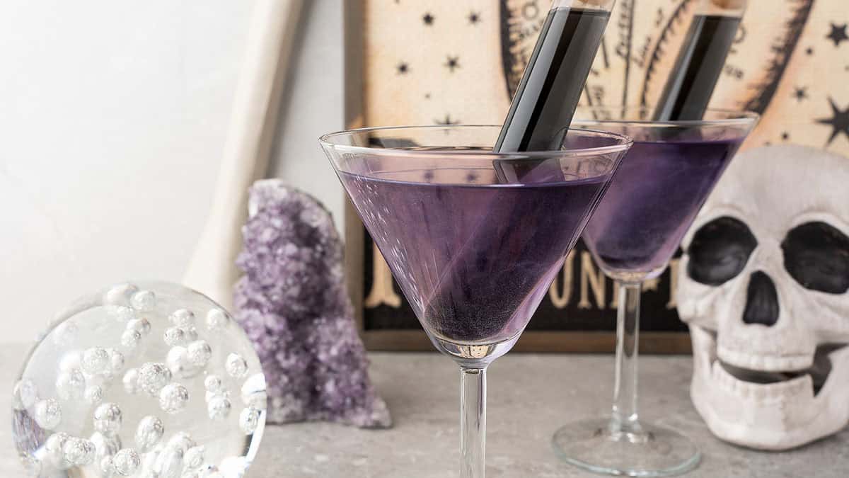 Purple and black rum Halloween cocktail with a dark layered color and spooky garnish.